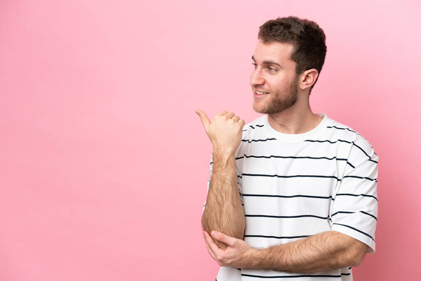 Young caucasian man isolated on pink background pointing to the side to present a product - Foto, immagini