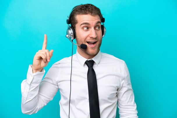 Telemarketer caucasian man working with a headset isolated on blue background intending to realizes the solution while lifting a finger up - Foto, afbeelding