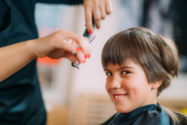 Child in hairdresser salon, getting a haircut - Foto, afbeelding