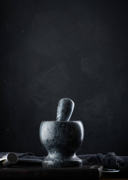 Black stone mortar on a wooden table - Фото, изображение