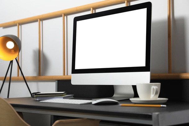 Modern computer with blank screen on black table indoors. Mockup for design - Photo, image