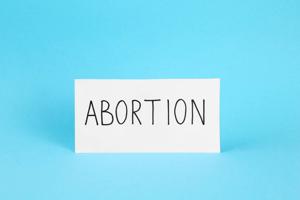 Paper note with word Abortion on light blue background - Фото, изображение