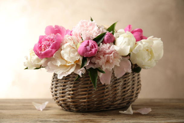 Beautiful peony bouquet in wicker basket on wooden table - Foto, immagini