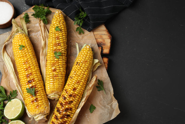 Tasty grilled corn on black table, flat lay. Space for text - Fotoğraf, Görsel
