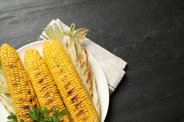 Tasty grilled corn on black table, space for text - Foto, imagen