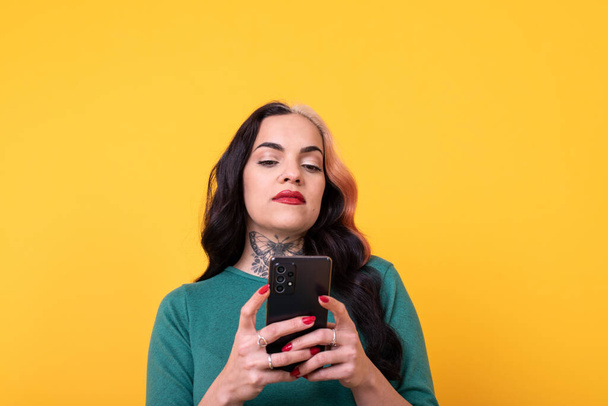 Портрет привабливої жінки з використанням смартфона на жовтому тлі. Студійний знімок
. - Фото, зображення