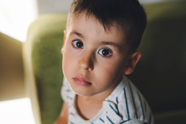 The portrait of a boy looking sadly straight into the camera. Head shot portrait. Little pretty preschooler boy. Lovely kid. - Valokuva, kuva