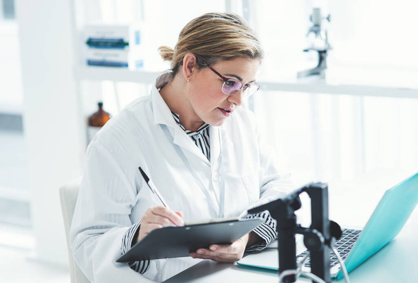 This looks like something Ive seen before. an attractive young female scientist filling a document while using a laptop in a laboratory - 写真・画像