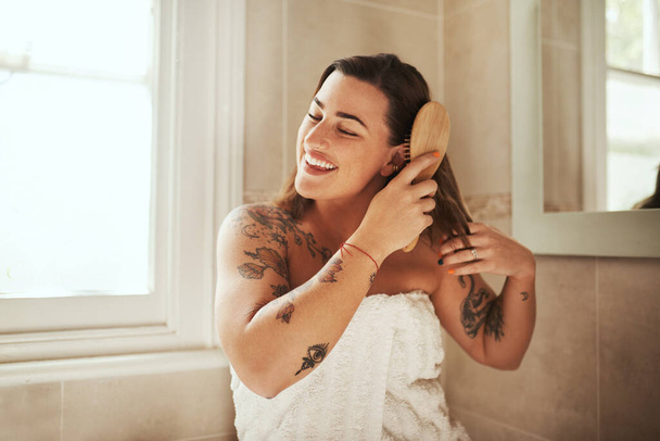 Love your hair and itll love you back. an attractive young woman brushing her hair during her morning beauty routine at home - Фото, изображение