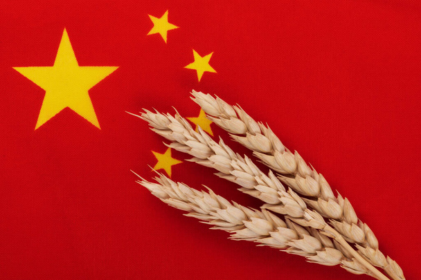 Three ripe ears of wheat against the background of a fragment of the flag of China - Foto, Bild