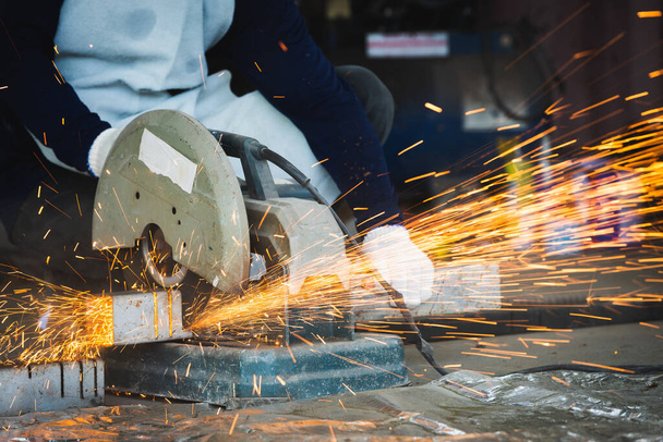 Cutting of a steel with splashes of sparks, Industrial grinder with sparks flying off of the wheel - Photo, image