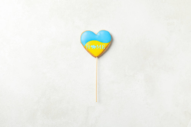 Cookie with Ukrainian flag colors and text HOME on light textured background - 写真・画像