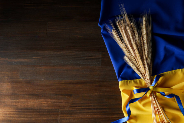 Ukrainian flag with spikelets with ribbons on wooden background - Φωτογραφία, εικόνα