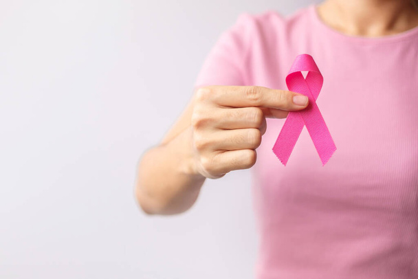Pink October Breast Cancer Awareness month, woman hand hold pink Ribbon and wear shirt for support people life and illness. National cancer survivors month, Mother and World cancer day concept - Photo, image