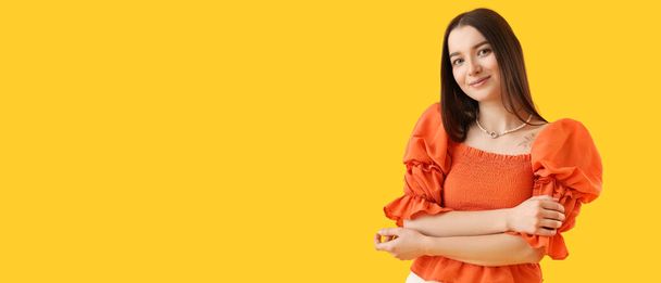Tattooed young woman wearing stylish pearl jewellery on yellow background with space for text - Foto, immagini