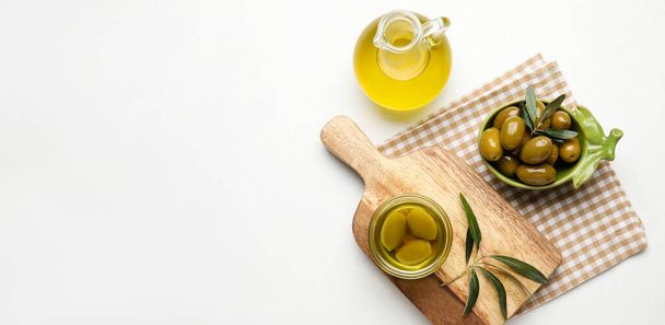 Composition with jug of oil and olives on white background with space for text - Foto, imagen