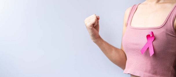 Розовый октябрь месяц рака молочной железы осведомленности, женщина держит в руках розовую ленту и носить рубашку для поддержки людей жизни и болезни. Национальный месяц переживших рак, концепция Всемирного дня борьбы с раком - Фото, изображение