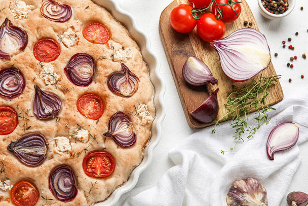 Composition with tasty Italian focaccia and ingredients on light background, closeup - Fotó, kép