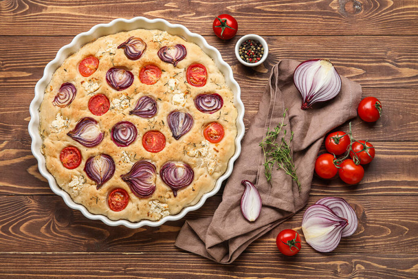 Composition with baking dish of tasty Italian focaccia and vegetables on wooden background - Photo, image