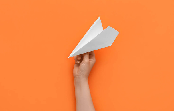 Женщина с бумажной плоскостью на оранжевом фоне - Фото, изображение