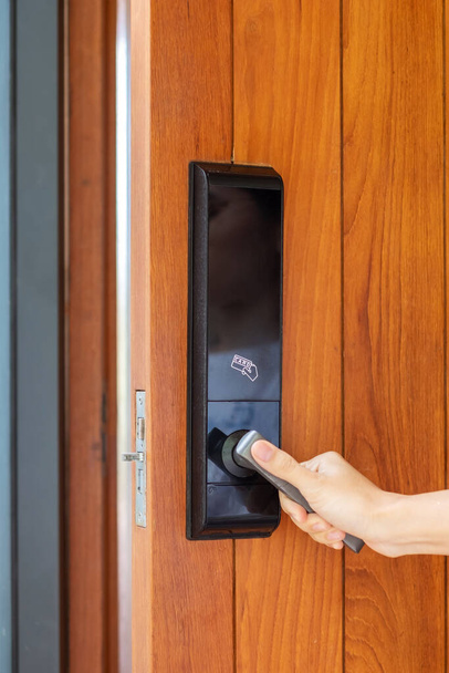 άνθρωπος κρατώντας λαβή έξυπνη ψηφιακή κλειδαριά πόρτα, ενώ ανοίξτε ή κλείστε την πόρτα. Έννοιες τεχνολογίας, ηλεκτρικού και τρόπου ζωής - Φωτογραφία, εικόνα