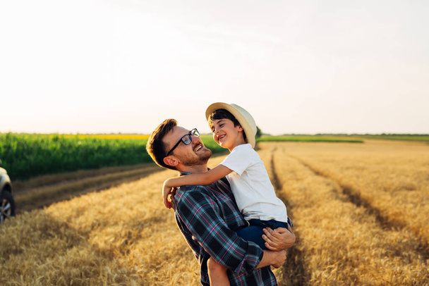 father and son in wheat field. father holding his son - 写真・画像