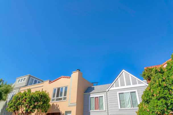 Фасад односемейных домов с традиционным дизайном и средиземноморским фасадом. Дома с низким углом обзора в Сан-Франциско, Калифорния против ясного голубого неба. - Фото, изображение