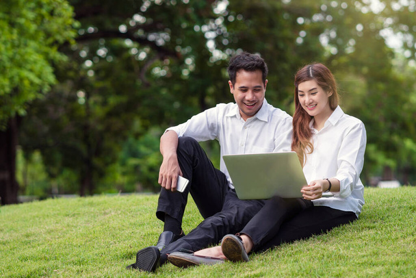 Happy asian couple college working via technology laptop with laughing action in the park, business and lifestyle concept - Foto, imagen