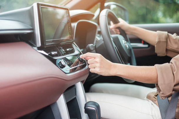 道路上の運転中に流れる空気の温度を調整する女性の手、車内のエアコン冷却システム。調整、温度と輸送の概念 - 写真・画像