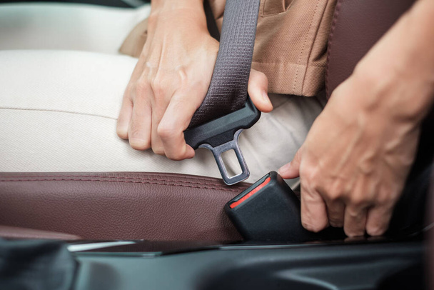 woman driver hand fastening seat belt during sitting inside a car and driving in the road. safety, trip, journey and transport concept - Photo, Image
