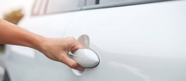 Hand holding smart car handle and opening a door. Transport, travel, service and car rental concept - Fotó, kép