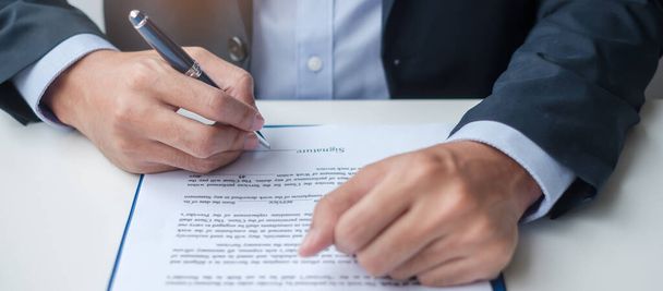 Podnikatel podepisuje smluvní dokumenty po přečtení, muž drží pero a schvalují na obchodní zprávu. Smlouvy, partnerství a řešení koncepcí - Fotografie, Obrázek
