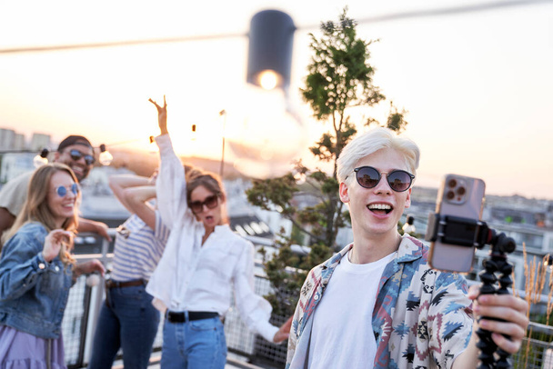 Caucasian young man make a video from rooftop party with friends in summer day - Foto, imagen