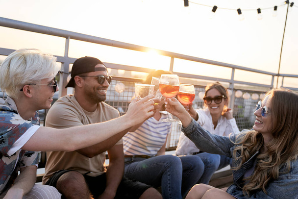 Group of friends make a toast during the sunset at the top of the roof - Foto, Imagen
