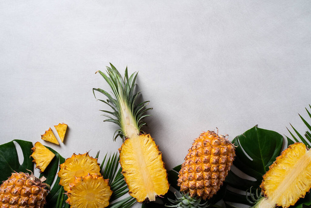 Top view of fresh cut pineapple with tropical leaves on dark blue background. - 写真・画像