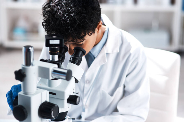 I simply have to solve this case. a young scientist using a microscope in a lab - Foto, Imagen