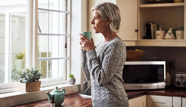 I needed this cup. a relaxed senior woman preparing a cup of tea with CBD oil inside of it at home during the day - Fotoğraf, Görsel