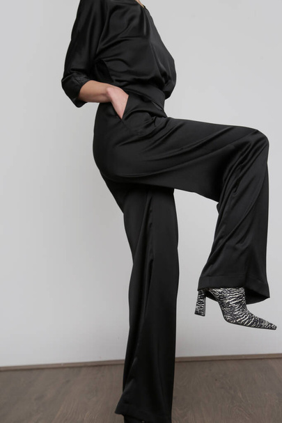Serie of studio photos of young female model wearing all black classic basic outfit, silk satin blouse and wide legged trousers. - Fotografie, Obrázek