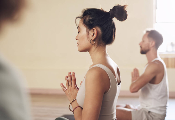 Yoga helps put our minds at ease. a group of young people meditating and practicing yoga together inside a yoga studio - Photo, image