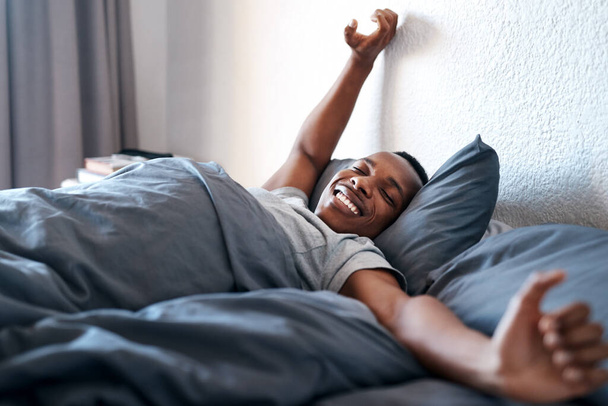 Rise and shine. a handsome young man lying in bed alone and stretching during a day off at home - Foto, imagen