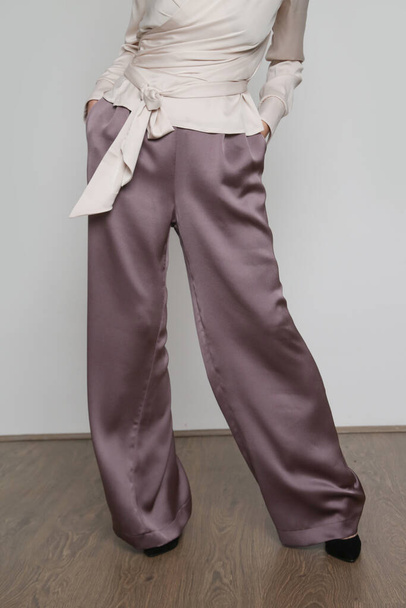 Serie of studio photos of young female model wearing silk satin wide legged trousers. - Fotoğraf, Görsel