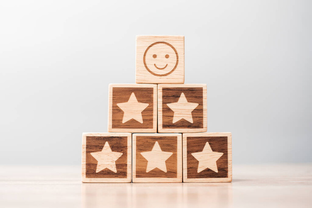 Emotionsgesicht und Sterne-Symbolblöcke auf dem Tischhintergrund. Service-Bewertung, Ranking, Kundenbewertung, Zufriedenheit, Bewertung und Feedback-Konzept - Foto, Bild