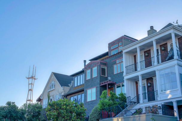 Крупные жилые здания с видом на башню Оро в Сан-Франциско, Калифорния. Рядом с домом стоит дом в геометрическом стиле с лестницей, слева - двускатная крыша. - Фото, изображение