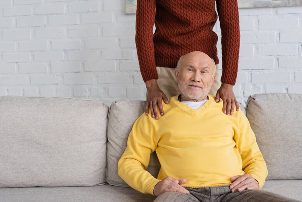African american man hugging granddad on couch at home  - Foto, Imagen