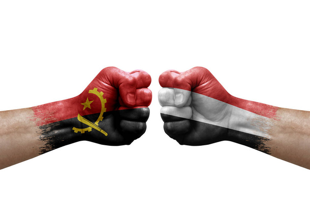 Two hands punch to each others on white background. Country flags painted fists, conflict crisis concept between angola and yemen - Photo, Image