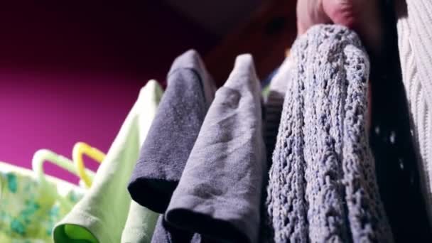 Looking for outfit on clothes hung on a rail medium 4k low shot slow motion selective focus - Imágenes, Vídeo