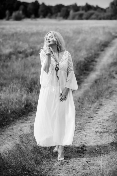 Ethnic hippie woman posing in boho long white lace dress at nature. Concept of ethnos style - Zdjęcie, obraz