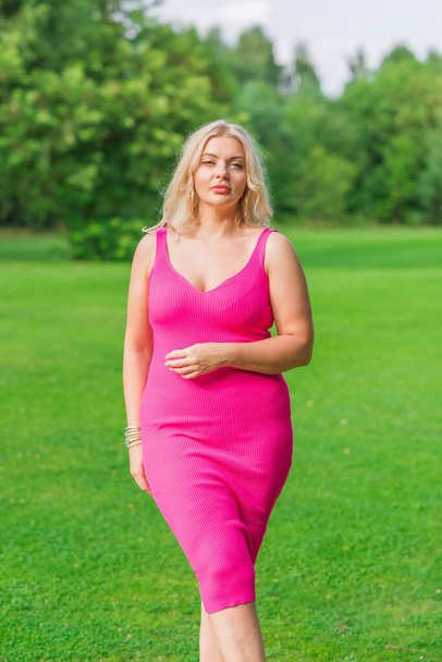 Συν το μέγεθος American ξανθιά γυναίκα σε ροζ midi φόρεμα στη φύση. Ζωή των ανθρώπων xl μέγεθος, ευτυχισμένη ωραία φυσική ομορφιά γυναίκα - Φωτογραφία, εικόνα