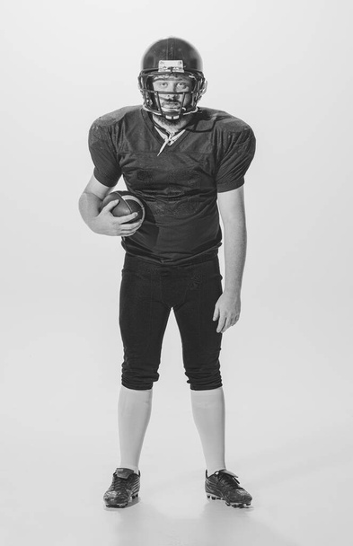 Black and white portrait of american football player in vintage style sports uniform isolated on white background. Concept of sport, eras comparison, timeless traditions, skills and ad - Fotografie, Obrázek