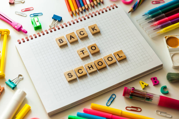 School office supplies and opened notebook on a desk with Back to school text made with wooden blocks - Φωτογραφία, εικόνα
